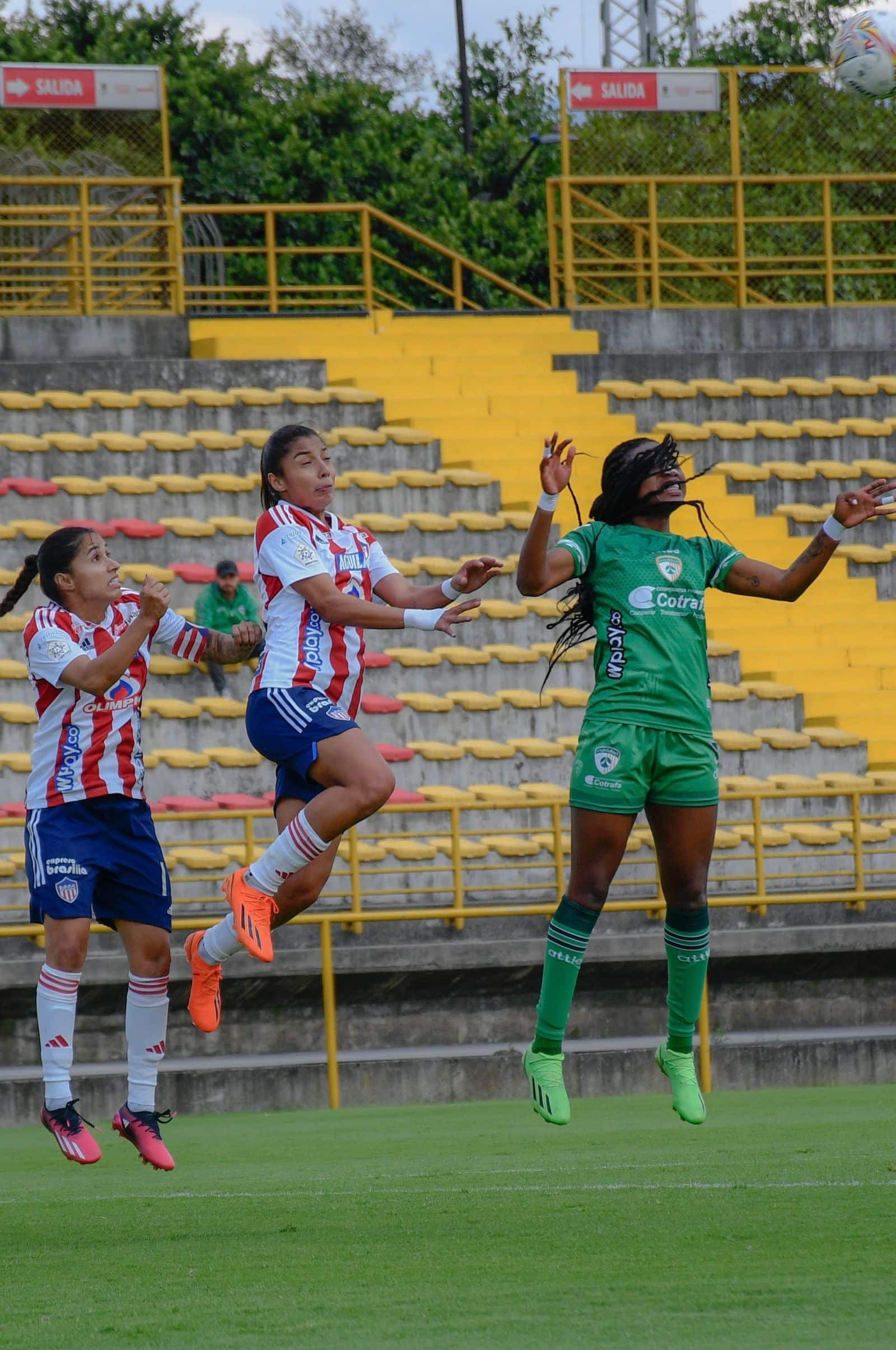 Deux joueuses de football féminin sautant pour disputer un ballon aérien dans un stade