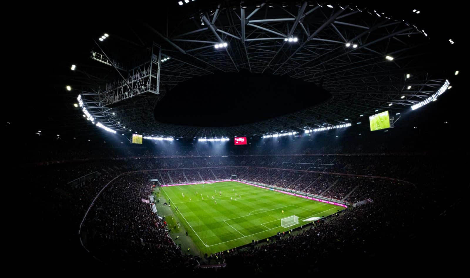 Vue aérienne nocturne d’un stade de football illuminé, tribunes combles